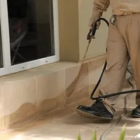 General pest control technician spraying exterior perimeter around a home in Dayton, OH